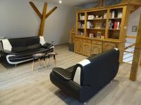 a living room with two black chairs and a book shelf at Gîte Le Cep d&#39;Or Alsace in Saint-Hippolyte