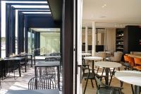 a restaurant with tables and chairs and a room with windows at Hotel du Bassin in Ostend