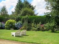 two white chairs sitting in the grass in a garden at Holiday Home Blaue Hortensie - SZN100 by Interhome in Sizun