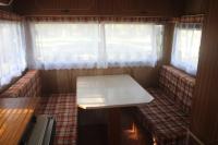 a table in the back of a room with windows at La Ptite Ferme de Caro in Meyrignac-lʼÉglise