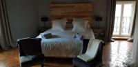 a bedroom with a large bed with two chairs at La Maison Josnes de Mady in Josnes