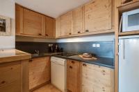 a kitchen with wooden cabinets and a stove top oven at Résidence Pierre &amp; Vacances Les Néréides in Belle Plagne