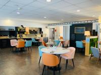 ein Restaurant mit Tischen und Stühlen und einer Küche in der Unterkunft Hotel Restaurant l'Eskemm St Brieuc-Trégueux in Tregueux