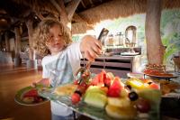 a young child is reaching for a tray of fruit at Novotel Lombok Resort & Villas in Kuta Lombok