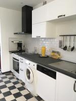 a kitchen with white cabinets and a washer and dryer at La Tanatte de wimereux sur la côte d opale in Wimereux