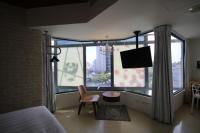a bedroom with a bed and a desk and a large window at Hotel Papa Whale-Kaohsiung Formosa Boulevard in Kaohsiung