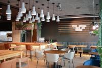 Un restaurante con mesas y sillas y un bar. en CVJM Jugendhotel München, en Múnich