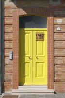a yellow door on the side of a brick building at ibagnanti in Porto Recanati