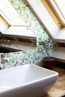 a white sink in a bathroom with green tiles at Les gerbes in Arras-en-Lavedan