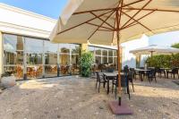 Un patio con mesas y sillas y una sombrilla. en Podere Fossarunza di Carlo Manzo, en Marsala