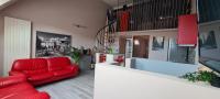 a living room with a red couch and a kitchen at L orée du Saint-Gangolphe in Lautenbach