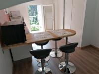 a small kitchen with a table and four bar stools at Le Clos Zinou in Lambesc