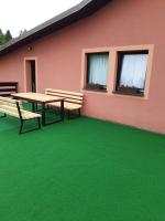 a patio with a table and benches on a green floor at Gorski cvijet in Delnice