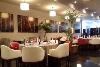 a dining room with tables and chairs and paintings at Wyndham Manta Sail Plaza Hotel and Convention Center in Manta