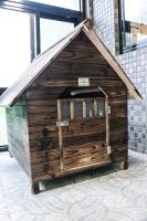 a wooden doghouse with a roof on a tile floor at Great Roots Forestry Spa Resort in Sanxia