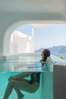 a woman laying in the water in a swimming pool at Aspaki by Art Maisons in Oia