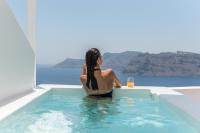 a woman sitting in a swimming pool with a glass of wine at Aspaki by Art Maisons in Oia