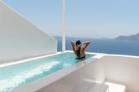 a woman sitting on the edge of a swimming pool at Aspaki by Art Maisons in Oia