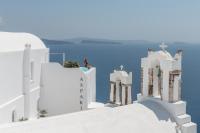 a person sitting on top of a white building at Aspaki by Art Maisons in Oia