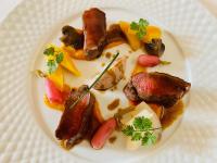 a white plate of food with meat and vegetables at Domaine de Suzel Hôtel & Spa in Vignieu