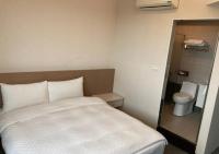 a small bedroom with a bed and a toilet at Shun-yi Business Hotel in Chiayi City