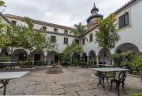a courtyard with tables and trees and a building at La Almoraima Hotel in Castellar de la Frontera