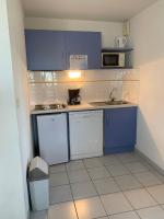 a small kitchen with blue cabinets and a sink at Résidence mayflower in Le Grau-du-Roi