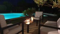 a table and two chairs and a pool at night at La Villa d&#39;Olivène in Cuers