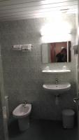 a bathroom with a sink and a toilet and a mirror at Hôtel Myosotis in Lourdes