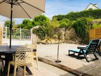 a patio with a table and chairs and an umbrella at Sur le chemin de la plage in Cherbourg en Cotentin