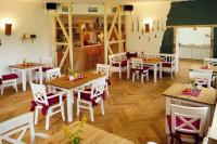ein Restaurant mit Holztischen und weißen Stühlen in der Unterkunft Erzgebirgshotel Misnia Bärenfels in Kurort Altenberg