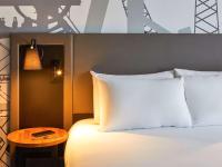 a bed with white pillows and a side table at Mercure Cardiff North Hotel in Cardiff