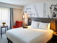 a hotel room with a large bed and a red chair at Mercure Cardiff North Hotel in Cardiff