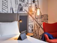 a bedroom with a bed and a red chair at Mercure Cardiff North Hotel in Cardiff
