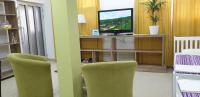a living room with two green chairs and a television at Apartment 18 in Pančevo
