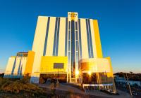 Un gran edificio amarillo y blanco con el sol brillando sobre él. en Travel Inn Hotels Caxias do Sul, en Caxias do Sul