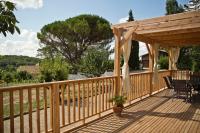 a wooden deck with a pergola and a table at Gîte Les Bourdettes in Auvillar