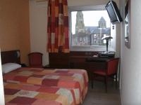 a bedroom with a bed and a desk and a window at Cit&#39;Hotel Saint Jacques in Parthenay