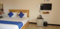 a bedroom with a bed with blue pillows and a tv at Paretto Seaview Hotel in Pantai Cenang
