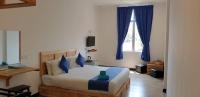 a bedroom with a large bed with blue curtains at Paretto Seaview Hotel in Pantai Cenang