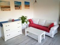 a white living room with a red couch and a dresser at Villa Wiese in Katzow