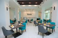 Hotel Casuarina@Kuala Kangsar في كوالا لكانغسار: غرفة طعام مع طاولات وكراسي زرقاء