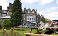una mujer sentada en una mesa de picnic en un parque en Cairn Hotel, en Harrogate