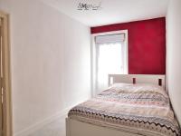 ein Schlafzimmer mit einem Bett mit einer roten Wand in der Unterkunft Appartement hypercentre au 2ème, ZOO - 24h du Mans in La Flèche