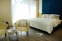 Un dormitorio con una gran cama blanca y una silla. en Hotel Athen Kelsterbach Frankfurt Airport, en Kelsterbach