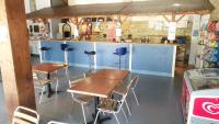 un restaurant avec deux tables et des chaises ainsi qu&#39;un comptoir dans l&#39;établissement Camping le Village de Florine, à Coëx