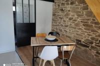 a table and chairs in a room with a stone wall at brelevenez 18 rue crec h quellien in Lannion