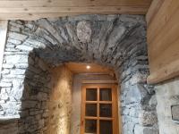 a door in a stone wall with a wooden ceiling at La Maison Trésallet in La Plagne Tarentaise