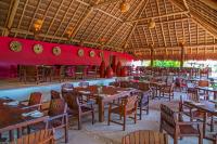 a restaurant with wooden tables and chairs and a red wall at The Explorean Selva Maya Kohunlich in Ruinas Kohunlích