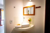 a bathroom with a sink with a mirror and flowers at Pousada Por do Sol in Trancoso